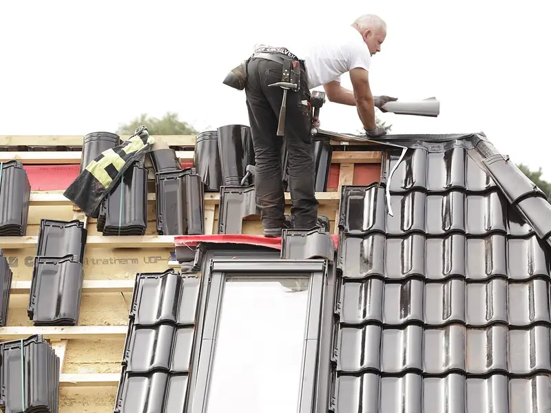 Roofer laying concrete roof tiles